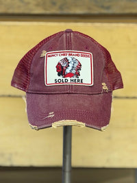Thumbnail for A distressed maroon trucker hat with a front patch reading 'Muncy Chief Brand Seeds' and 'Sold Here,' displayed on a stand against a yellow wooden background.