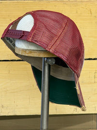 Thumbnail for A distressed trucker-style baseball cap with a burgundy mesh front, white mesh back, and a dark green fabric brim, displayed on a wooden stand against a light wood plank background.