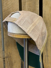 Thumbnail for A beige mesh-back baseball cap with a tan adjustable strap and a white ribbed front panel, displayed on a wooden stand against a rustic wood plank background.