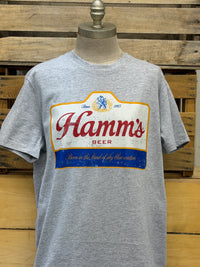 Thumbnail for A heather gray short-sleeve t-shirt displayed on a mannequin torso, featuring a large vintage-style printed graphic of the 'Hamm's Beer' logo on the chest