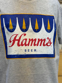 Thumbnail for A close-up of a heather gray t-shirt featuring a distressed vintage-style graphic of the classic Hamm's Beer logo, with blue, white, and red colors and yellow pine tree accents.