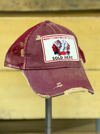 Thumbnail for A distressed maroon trucker cap with a white rectangular patch on the front that reads 'MUNCY CHIEF BRAND OFFICE SOLD HERE' with a red and white graphic, displayed on a stand against a yellow wooden background.