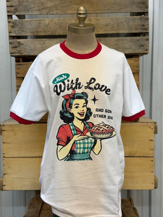 A vintage-style ringer t-shirt displayed on a wooden dress form mannequin. The white short-sleeve shirt features red ribbed collar and sleeve cuffs, and a retro graphic of a woman holding a pie with the text 'Made With Love' and 'AND SON OTHER SIN'.