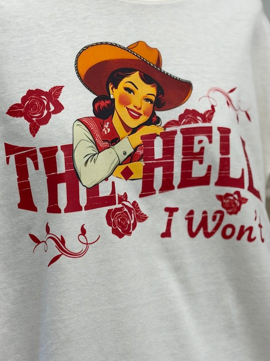 A close-up of a white heather t-shirt featuring a graphic print of a pin-up style woman in a cowboy hat with red roses and the text 'THE HELL I Won't' in red.
