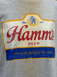 Thumbnail for Close-up of a heather gray sweatshirt featuring a distressed vintage-style print of the Hamm's Beer logo with red lettering, a blue banner, and gold accents.